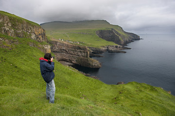 Photographer taking pictures on Mykines, Faroe Islands