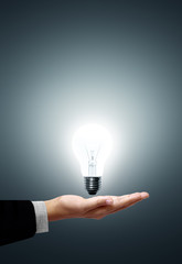 Light bulb in hand businessman on gray background
