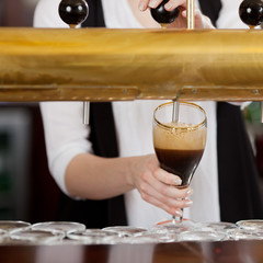 kellnerin zapft dunkles bier