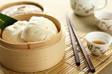 Dimsum in a bamboo basket by tea pot and cups