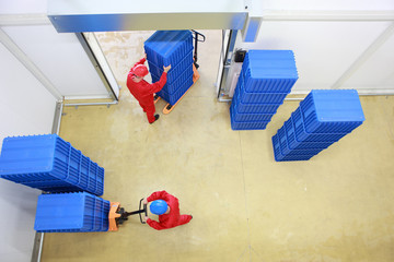 two workers loading plastic boxes in small warehouse