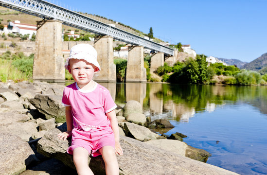 little girl sitting at railway viaduct in Douro Valley, Portugal