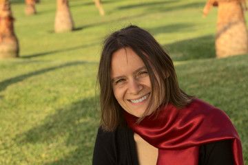 Portrait of a smiling young woman with a red scarf in a park