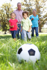 Fototapeta premium Grandparents playing football with grandchilderen