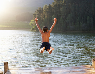 Fototapeta Young boy jumping into lake obraz