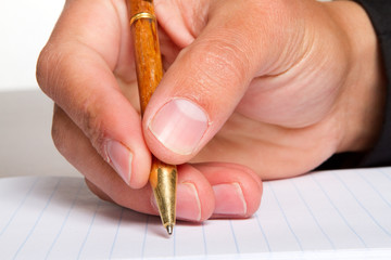 A close up of a man writing in a notebook