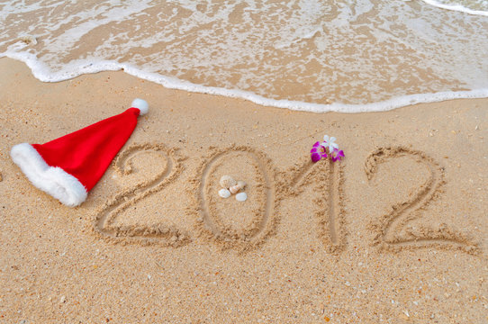 Numbers 2012 and santa hat on tropical beach sand