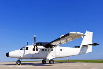 Twin propeller airplane on a runway.