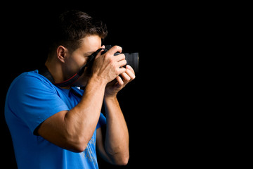 Young photographer with camera against black background