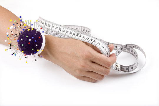 Hand with pincushion and measuring tape