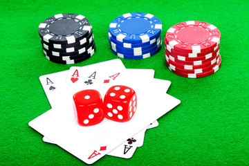 four aces playing cards and red dice on green background