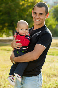 Portrait of young father and his little son in park