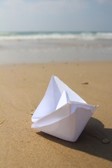 Origami paper boat on the sand at the beach