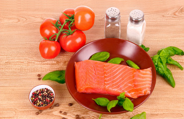 Red fish on the plate with pepper and green leaves