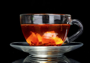 black tea and fruit in cup on black  background