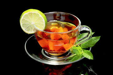 black tea and fruit in cup on black background