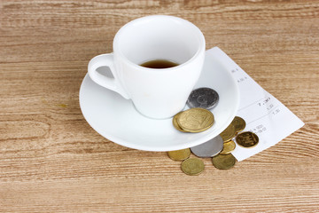 Empty cup of coffee with coins tip on wooden background. Ukraini