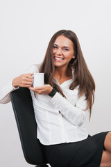 gorgeous young woman giving you warm smile while drinking tea.