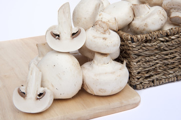 Fresh champignon mushrooms in rustic basket isolated on white