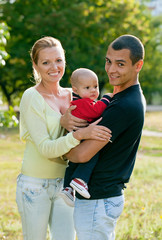 Fototapeta premium Portrait of happy young couple with baby son in park