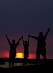 Fototapeta na wymiar The family from three persons welcomes the sunset sun