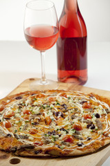 Delicious pizza with rose wine on a wood board