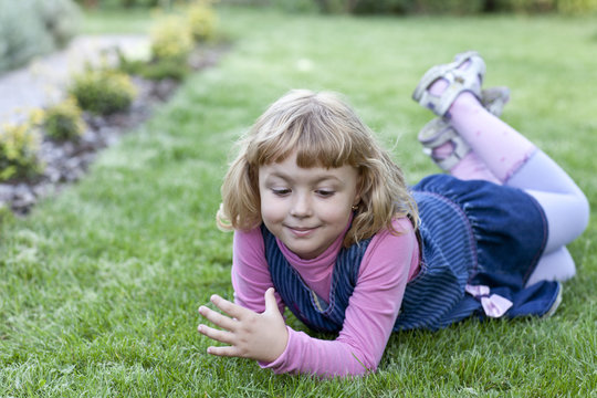 The little girl lies on a lawn