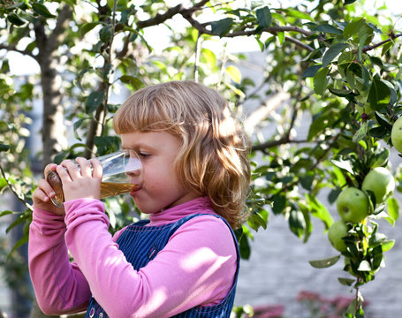 Portrait of little girl driking an apple juice