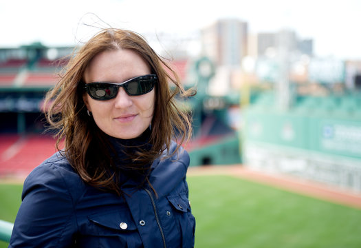 Young woman in sunglasses visiting a baseball park