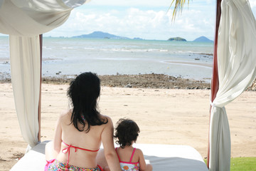 young lovely mother and her little daughter on tropical white be