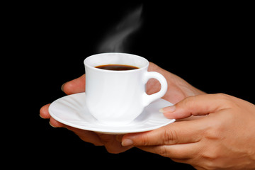 Hands with a cup of coffee with steam on a black background