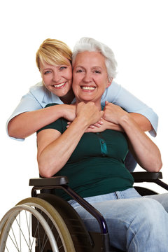 Frau umarmt Seniorin im Rollstuhl