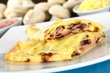 Rolled crepes filled with ham, cheese and mushroom