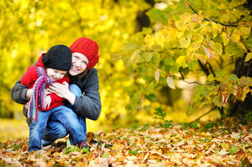 Young mother and her toddler girl have fun in autumn