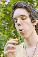 Young man blowing on a dandelion