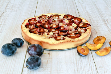 Plum pie and plums on a wooden white background