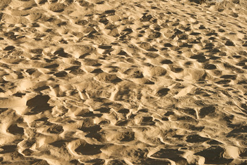 Sand background with traces of feet. Textural drawing.