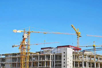 Crane and building construction site against blue sky