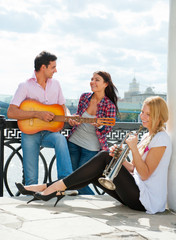 Young friends play the guitar and trumpet