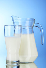 Tasty milk in jug and glass on blue background