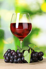 Ripe grapes and  glass of wine on  green background
