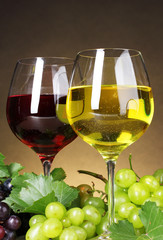 Glasses of wine and grapes on yellow background