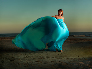 woman on beach wind blowing blue dress