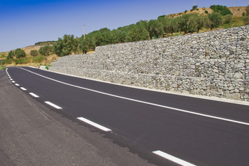 Strada asfaltata con muro di sostegno in curva