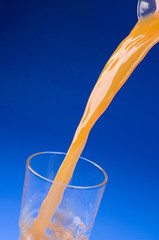 Pouring fresh orange juice over blue