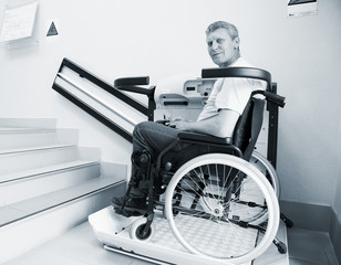 man in an invalid chair walks upstairs