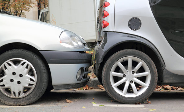 Two Cars Parallel Parked Less Than An Inch From Each Other.