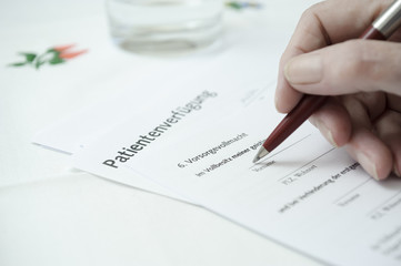 seniorenhand füllt eine Patientenverfügung aus