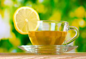 tea with lemon on green leaves background