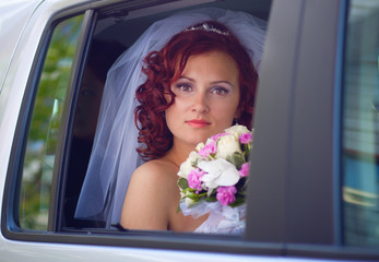 Happy bride in window a wedding car.